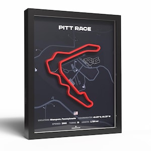 Peut inclure: Tableau encadré représentant le circuit de Pitt Race en rouge sur fond gris foncé. Le texte "PITT RACE" est en haut. Le cadre est noir. Le texte supplémentaire comprend l'emplacement, les coordonnées et les détails de la piste.