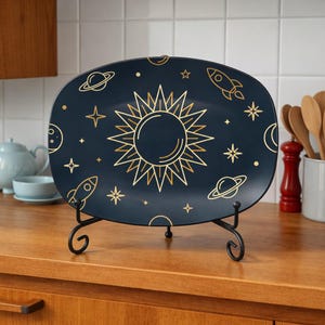 May include: A navy blue rectangular serving platter with a gold celestial design. The design includes a sun, stars, planets, and rockets. The platter is displayed on a black metal stand, perfect for serving appetizers or desserts.