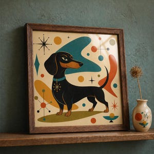 May include: Framed mid-century modern art print featuring a black dachshund dog with a blue collar and a snowflake pendant. The artwork has a retro color palette with teal, orange, and yellow shapes. The print is in a brown wooden frame.