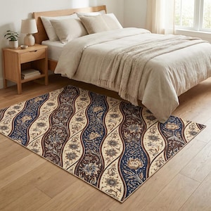 Puede incluir: Una alfombra rectangular con un patrón ondulado repetido de diseños florales en azul marino, crema y marrón. La alfombra está colocada sobre un suelo de madera en un dormitorio, con una cama y una mesita de noche visibles en el fondo.