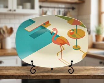 Puede incluir: Una fuente decorativa rectangular con un diseño de flamenco. La fuente presenta un flamenco, una piscina y una mesa con una bebida. La paleta de colores incluye verde azulado, naranja, amarillo y beige. La fuente se muestra en un soporte de metal negro.