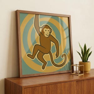 May include: A framed print featuring a cartoon monkey in shades of brown, hanging from a curved arm. The background has concentric circles in teal and yellow. The frame is a dark wood color.