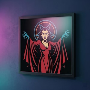 Puede incluir: Obra de arte enmarcada que representa a una mujer vampiro estilizada con un vestido rojo con mangas largas y manos azules con garras. La obra tiene un fondo negro con un pentagrama y un diseño circular. El marco es negro.