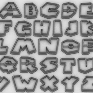 May include: A collection of gray plastic alphabet cookie cutters. Each letter of the alphabet is represented, from A to Z, in a bold, blocky font. The cutters are designed with a thick border for easy handling and consistent shapes.