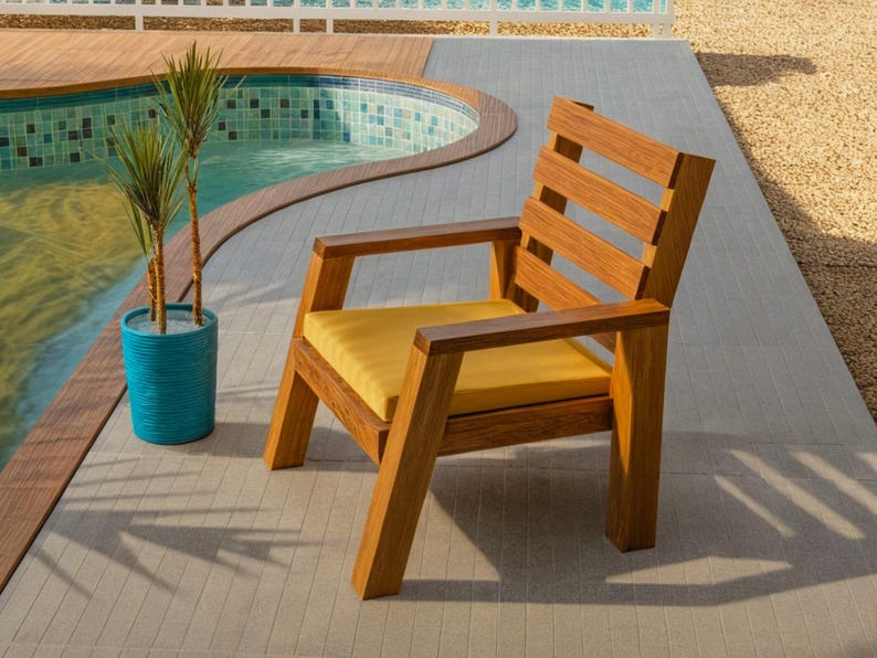 May include: A wooden outdoor chair with a yellow cushion. The chair has a slatted back and armrests. It is placed on a light gray tiled surface next to a swimming pool. A blue planter with plants is nearby.