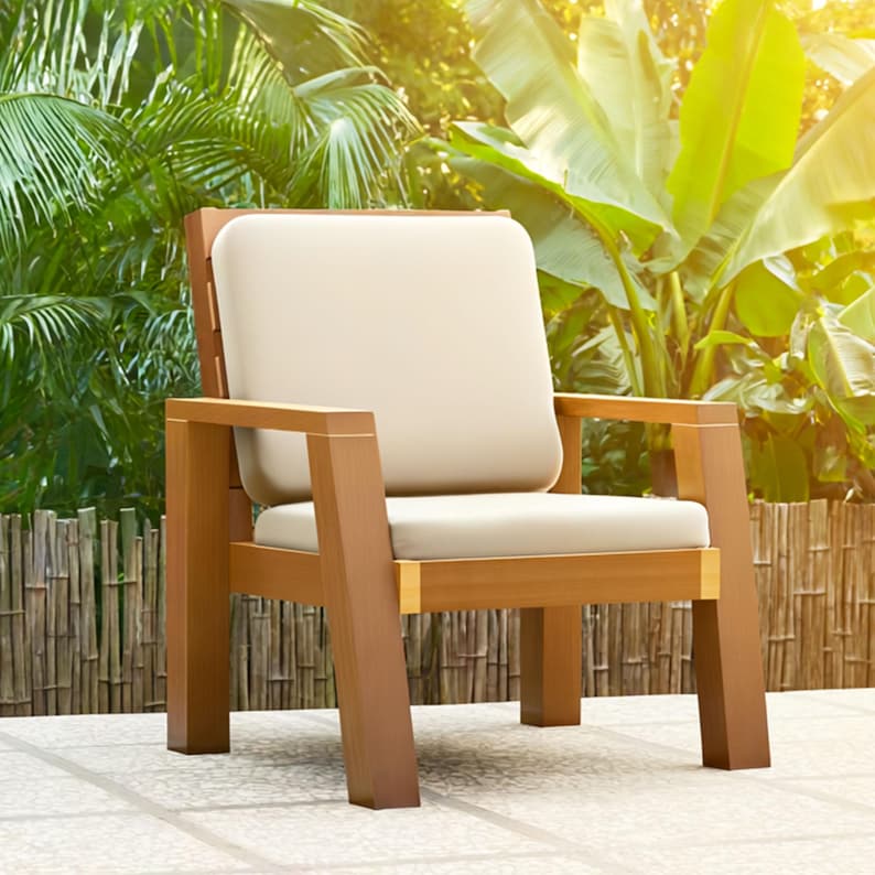 May include: A wooden outdoor armchair with a light beige cushion and backrest. The chair has a natural wood finish and is set against a backdrop of lush green foliage and a bamboo fence. The chair's dimensions are approximately 30 inches wide, 30 inches deep, and 30 inches high.