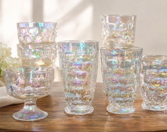 May include: A collection of clear glass drinkware and bowls featuring an iridescent finish and a raised, repeating honeycomb texture. The set includes various sizes of tumblers and footed bowls, all displaying a multi-colored, pearlescent sheen.