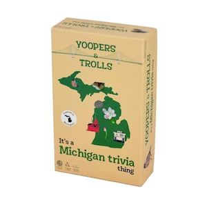 May include: A tan box of "Yoopers & Trolls" Michigan trivia game. The box features a green outline of Michigan with illustrations of landmarks and wildlife. Text on the box reads "It's a Michigan trivia thing."