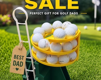 May include: A green and yellow plastic golf ball dispenser holding multiple white golf balls, featuring a white handle and a brown cardboard tag with the text BEST DAD and a heart symbol. The text FATHER'S DAY SALE and PERFECT GIFT FOR GOLF DADS appears above.