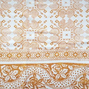 Peut inclure: Tissu blanc avec un motif répété de formes géométriques brunes. Le tissu a une bordure avec un motif répété de cercles bruns et de motifs floraux.