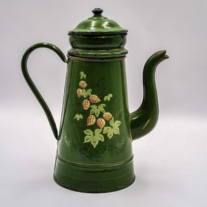 Könnte beinhalten: Eine grüne Emaille-Kaffeekanne mit Blumenmuster. Die Kanne hat einen Deckel und einen Ausguss. Das Blumenmuster zeigt grüne Blätter und gelbe Blüten.