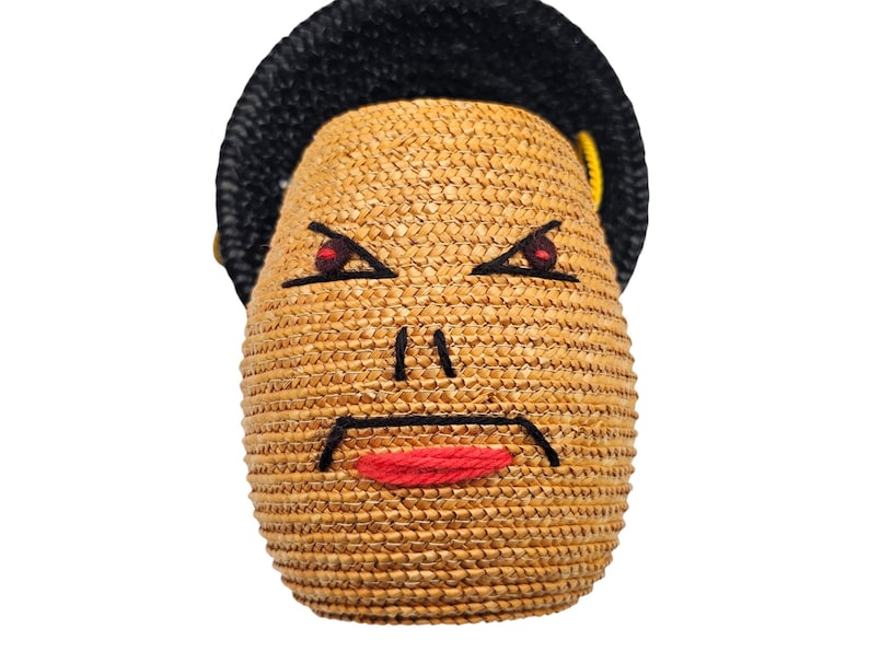 Close up of wool embroidered face on vintage straw handbag