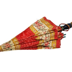 Antique French child's parasol in cretonne fabric with a design of floral garlands and cherubs in oval medallions, in tones of coral, pink, beige, honey and sage green, wooden handle with hand painted face.
