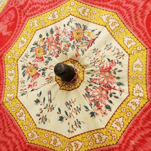 Antique French child's parasol in cretonne fabric with a design of floral garlands and cherubs in oval medallions, in tones of coral, pink, beige, honey and sage green, wooden handle with hand painted face.