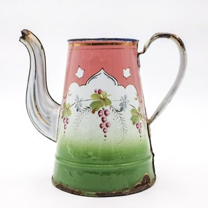Könnte beinhalten: Eine antike Emaille-Teekanne mit einem floralen Design in Rosa, Weiß und Grün. Die Teekanne hat einen Ausguss und einen Henkel.
