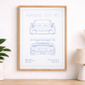 Puede incluir: Una impresión enmarcada con un dibujo lineal azul de un Porsche GT3 RS. La impresión muestra vistas delantera y trasera del coche, además de detalles como el tamaño del motor, la potencia y el tiempo de 0-100 km/h. El marco es de madera clara.