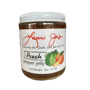 Puede incluir: Un tarro de gelatina de pimiento y melocotón con tapa y etiqueta blancas. La etiqueta presenta el texto "Lauri Jo's" en escritura roja, con "Peach pepper jelly" debajo. El tarro contiene 227g de gelatina.