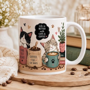 May include: White ceramic coffee mug with a whimsical cat and coffee design. The mug features illustrations of cats, coffee beans, and the text "Life is BETTER with CATS & COFFEE". The mug also has the text "PURR FECT BLEND", "COFFEE FUEL CAT NAPS", "MEOW", and "CAT LATER".