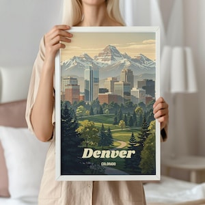 May include: A framed art print featuring a stylized illustration of the Denver, Colorado skyline. The artwork depicts a cityscape with mountains in the background, a park in the foreground, and the city's name in white text.