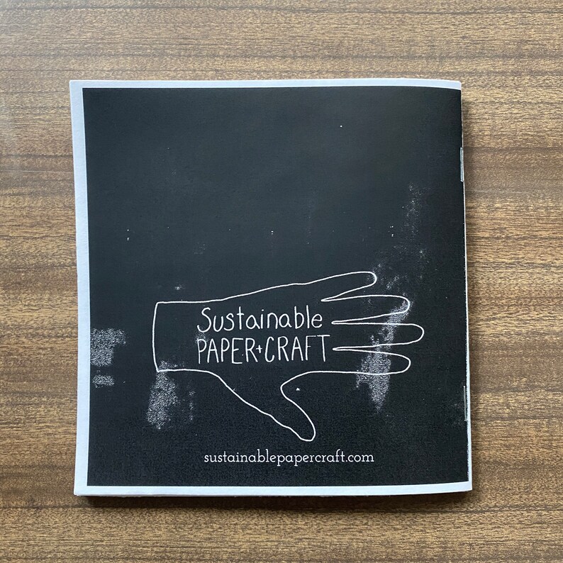 May include: Black and white image of a hand with the text "Sustainable Paper+Craft" and the website address "sustainablepapercraft.com" below.
