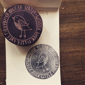 May include: Two black and white rubber stamps with the text "Little Free Library - Please Return to Musser Park" and a small bird illustration. The text is in a circular pattern around the bird.
