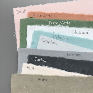 May include: A stack of paper samples in various shades of green, blue, gray, brown, and pink. The paper is textured and has a handmade look. The names of the colors are written on the paper, including Blush, Terra Cotta, Terre Verte, Natural, Celadon, Graphite, Carbon, Buff, Bistre, and Paynes.