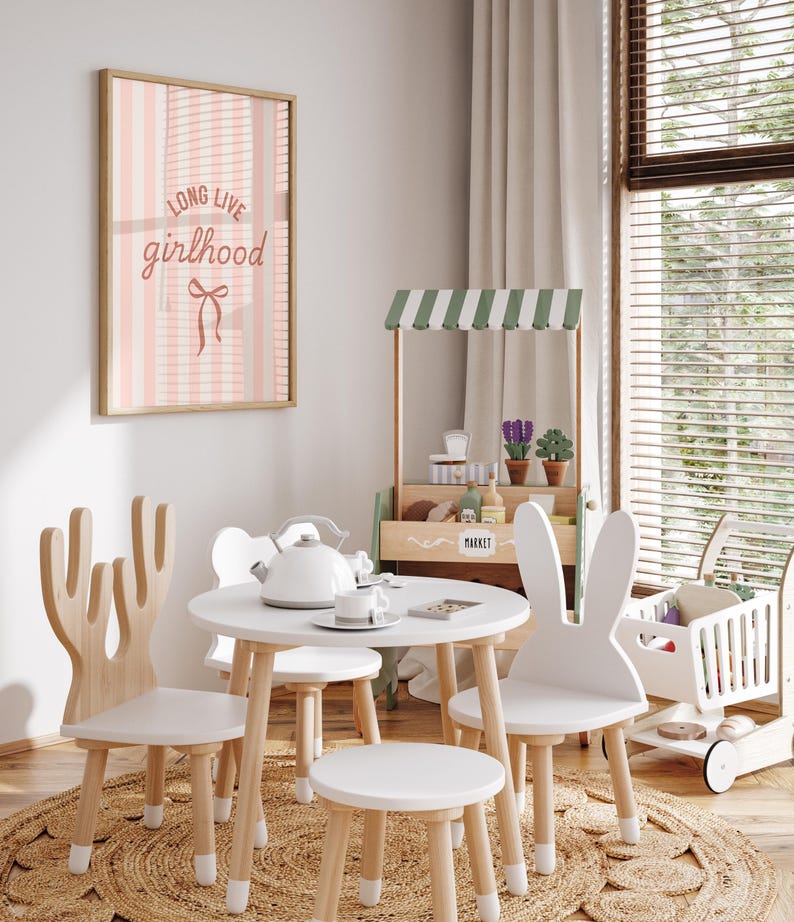 A cozy and inviting children's playroom with a pink and white striped wall hanging, a wooden play stand with a green and white striped awning, and a small table with a teapot and cups.