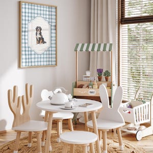 A cozy and charming children's playroom with a table, chairs, and a toy tea set, featuring a framed picture of a dog on the wall.