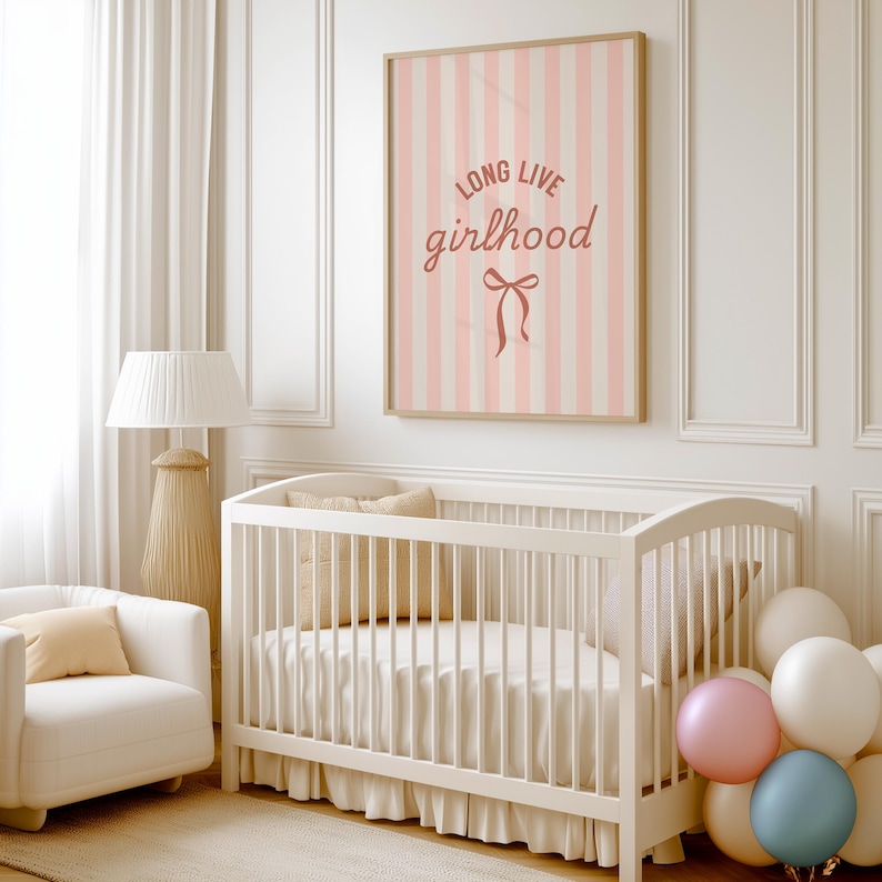 A white crib with a pink and white striped poster above it, a white chair, and a bunch of balloons in the corner of the room.