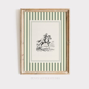 May include: A framed print with a monochrome illustration of a jockey on a horse. The print has a cream background, a green and white striped border, and a gold-coloured frame. The text "PENNY LETTER STUDIO" is at the bottom of the print.