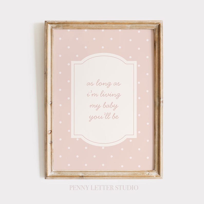 A framed print with a pink background and white polka dots, featuring a message that reads "as long as I'm living my baby you'll be".