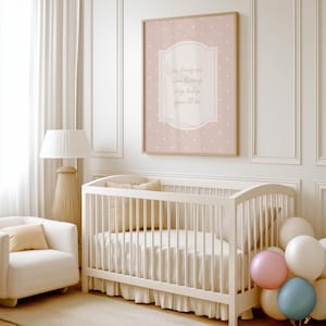 A cozy nursery with a white crib, a white chair, and a lamp. Above the crib is a framed poster with the text "as long as I'm living my baby will be".