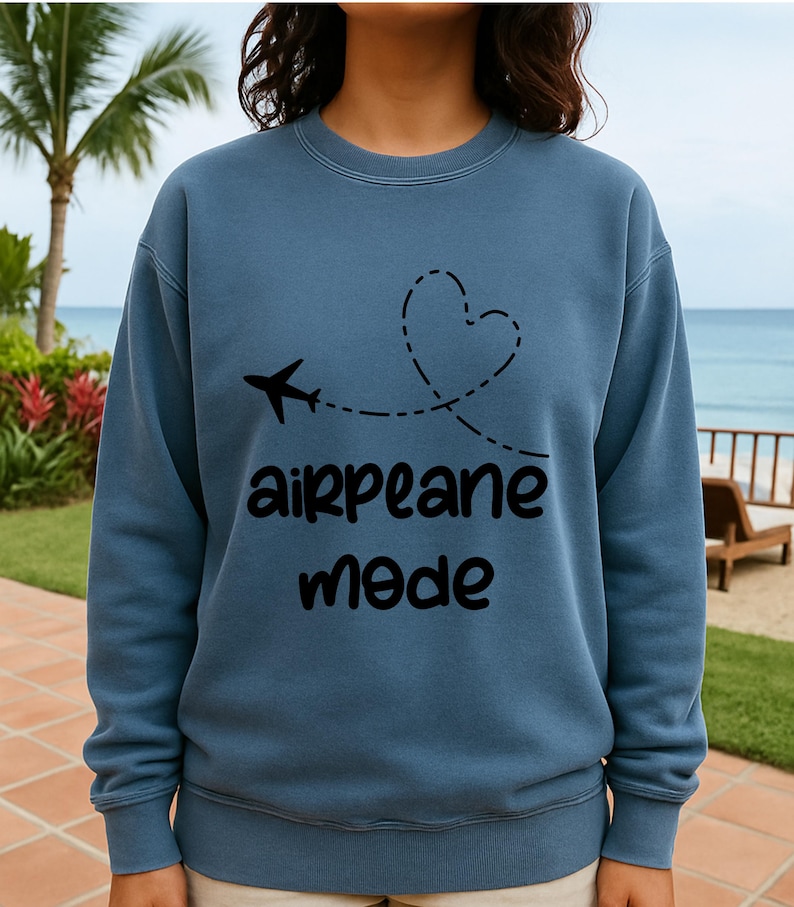 May include: A blue sweatshirt with a black airplane graphic and the words "airplane mode." The airplane's flight path forms a heart shape. The sweatshirt is a solid color and has a crew neck.