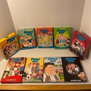 Op de afbeelding: Negen DVD-hoezen van Family Guy, volumes 2 tot en met 9. De hoezen zijn rood, geel en blauw met een cartoonafbeelding van de personages uit de serie op de voorkant.