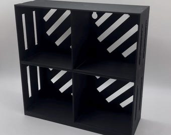 Könnte beinhalten: Ein schwarzes Regal mit vier Fächern und diagonalen weißen Streifen, die in die Seiten geschnitten sind. Das Regal hat ein modernes Design und eignet sich zum Ausstellen von Gegenständen. Das Regal besteht aus einem soliden Material und hat eine matte Oberfläche.