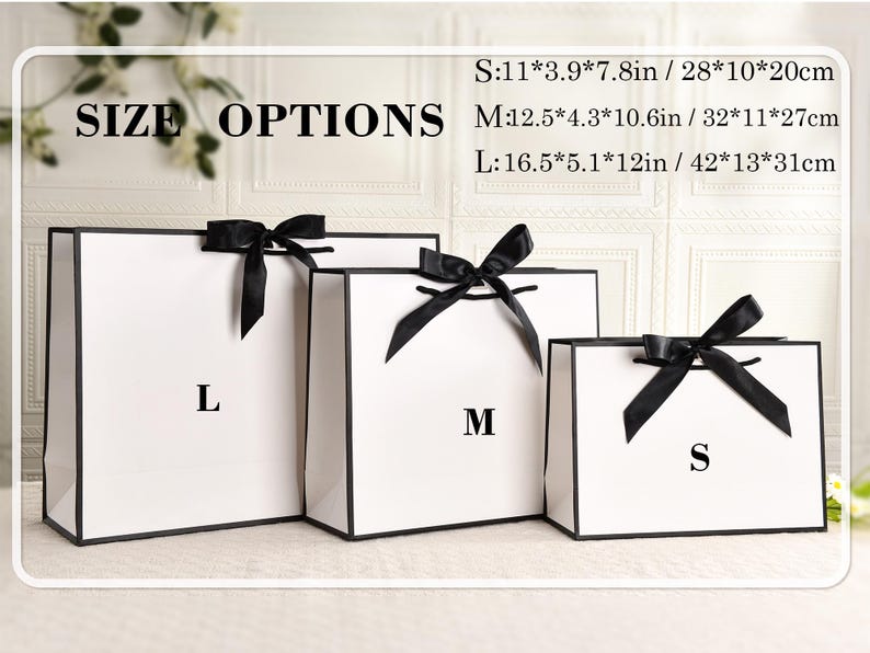 May include: Three white gift bags with black trim and black ribbon bows. The bags are labeled S, M, and L, with size options listed in inches and centimeters. The text "SIZE OPTIONS" is at the top.