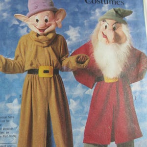Könnte beinhalten: Kostüme von Dopey und Grumpy Dwarf von Disney. Dopey trägt einen lila Hut, eine braune Hose und einen gelben Gürtel. Grumpy trägt einen grünen Hut, eine rote Hose und einen weißen Bart.