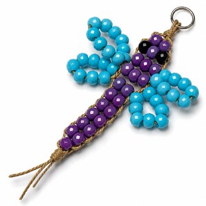 May include: A beaded dragonfly keychain. The dragonfly features turquoise and purple beads, with black beads for the eyes. The body is made of purple beads, and the wings are turquoise. The keychain is attached to a woven cord.