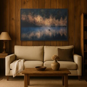 May include: A framed landscape art print depicting a serene lake scene with a single bird. The artwork features a misty atmosphere, with trees silhouetted against a sunrise or sunset. The color palette includes blues, oranges, and browns.