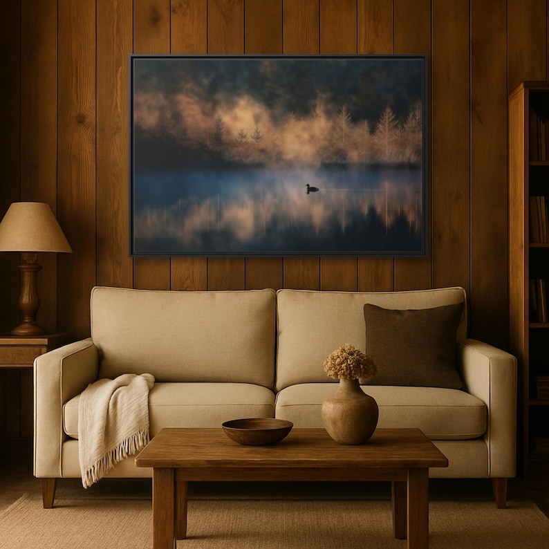 May include: A framed landscape art print depicting a serene lake scene with a single bird. The artwork features a misty atmosphere, with trees silhouetted against a sunrise or sunset. The color palette includes blues, oranges, and browns.