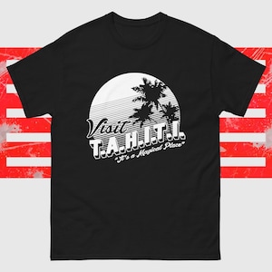 May include: Black t-shirt with a white graphic. The design features the words "Visit T.A.H.I.T.I." above the phrase "It's a Magical Place." The graphic includes a white sun with horizontal lines and palm trees.