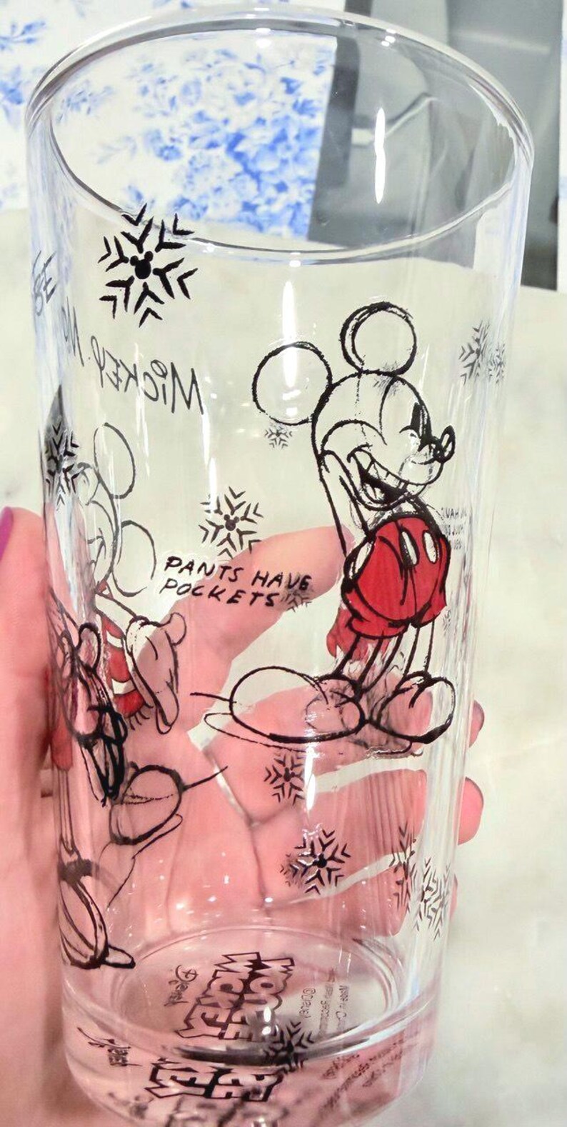Pu&ograve; includere: Bicchiere trasparente con un disegno di Mickey Mouse nero e rosso, con motivi a fiocco di neve. Il testo "Pants Have Pockets" &egrave; visibile. Il bicchiere &egrave; cilindrico e sembra essere un bicchiere da bere.