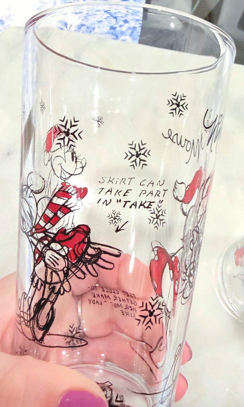 Pu&ograve; includere: Bicchiere trasparente con un'illustrazione di un personaggio dei cartoni animati in abito rosso e bianco, con fiocchi di neve e testo. Il testo recita "SKIRT CAN TAKE PART IN TAKE".