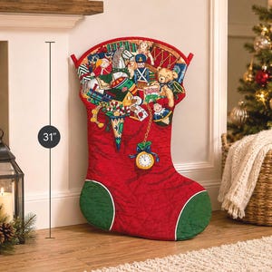 Könnte beinhalten: Ein 79 cm großer, gesteppter Weihnachtsstrumpf in Rot und Grün mit einem detaillierten Aufdruck von Spielzeug, darunter ein Teddybär, ein Nussknacker, ein Zug und eine Taschenuhr. Der Strumpf hat ein rotes Bündchen sowie eine grüne Spitze und Ferse.