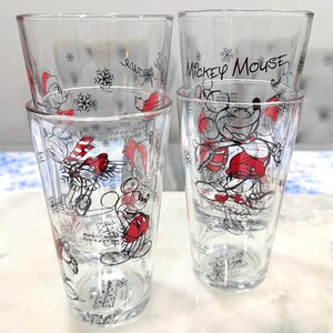Pu&ograve; includere: Set di quattro bicchieri trasparenti con disegni invernali di Topolino. Ogni bicchiere presenta una diversa illustrazione di Topolino in rosso, nero e bianco, con fiocchi di neve e la scritta "Mickey Mouse" su alcuni.