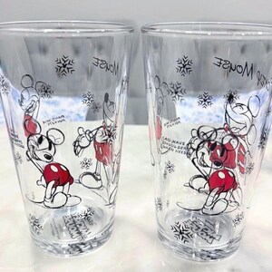 Pu&ograve; includere: Due bicchieri trasparenti con un design di Topolino. I bicchieri presentano un'illustrazione di Topolino in bianco e nero e rosso, fiocchi di neve e testo. Il testo include "Mickey Mouse" e "Can have shoulder when needed."