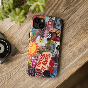 May include: A colorful phone case with a collage of stickers, including a smiling flower, an eight ball, and the words "Take it easy." The case has a variety of colors and patterns, including red, yellow, blue, and pink.