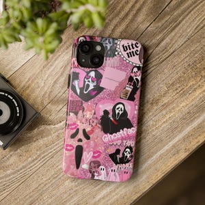 May include: A pink phone case with a collage design featuring the Ghostface mask from the Scream movies. The case has a glittery background and includes hearts, lips, and the text "bite me" and "Ghostface".