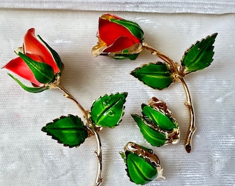 Set of two enameled gold tone Giovanni rose brooches, one pink coral and one red, with matching clip on green leaf earrings, circa 50s 60s