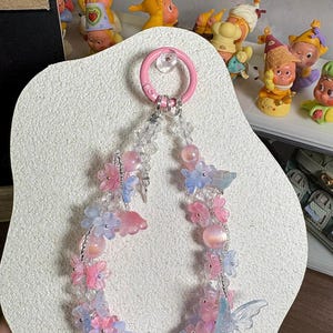 Handgefertigter Blumenkristall-Telefon-Charme-Schlüsselanhänger, zarte Blumen-Perlen-Handy-hängende Verzierung mit Schmetterlings-Akzenten, Pastellfarbschema